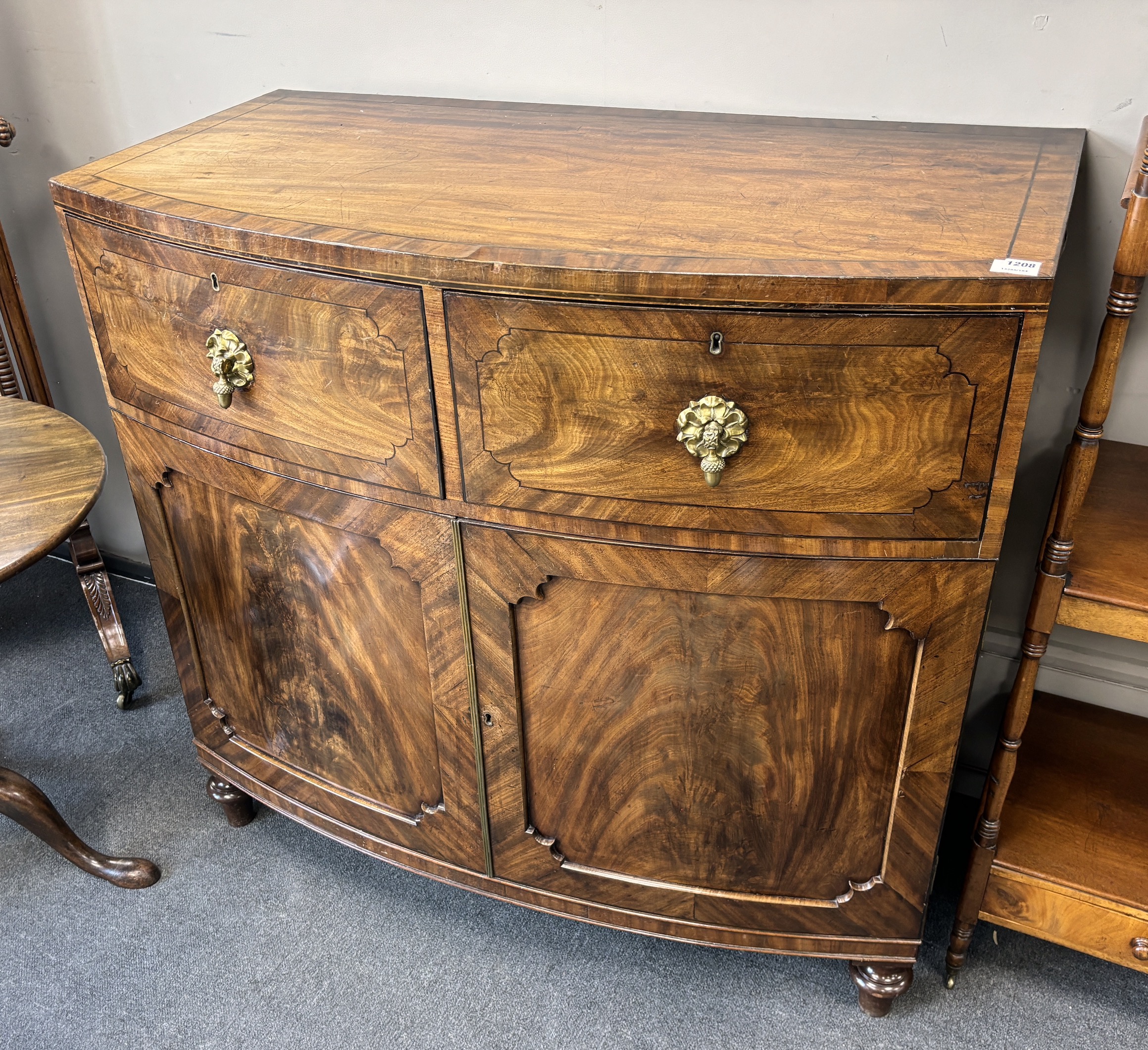 A George IV flame mahogany bowfront press cupboard, width 115cm, depth 61cm, height 108cm